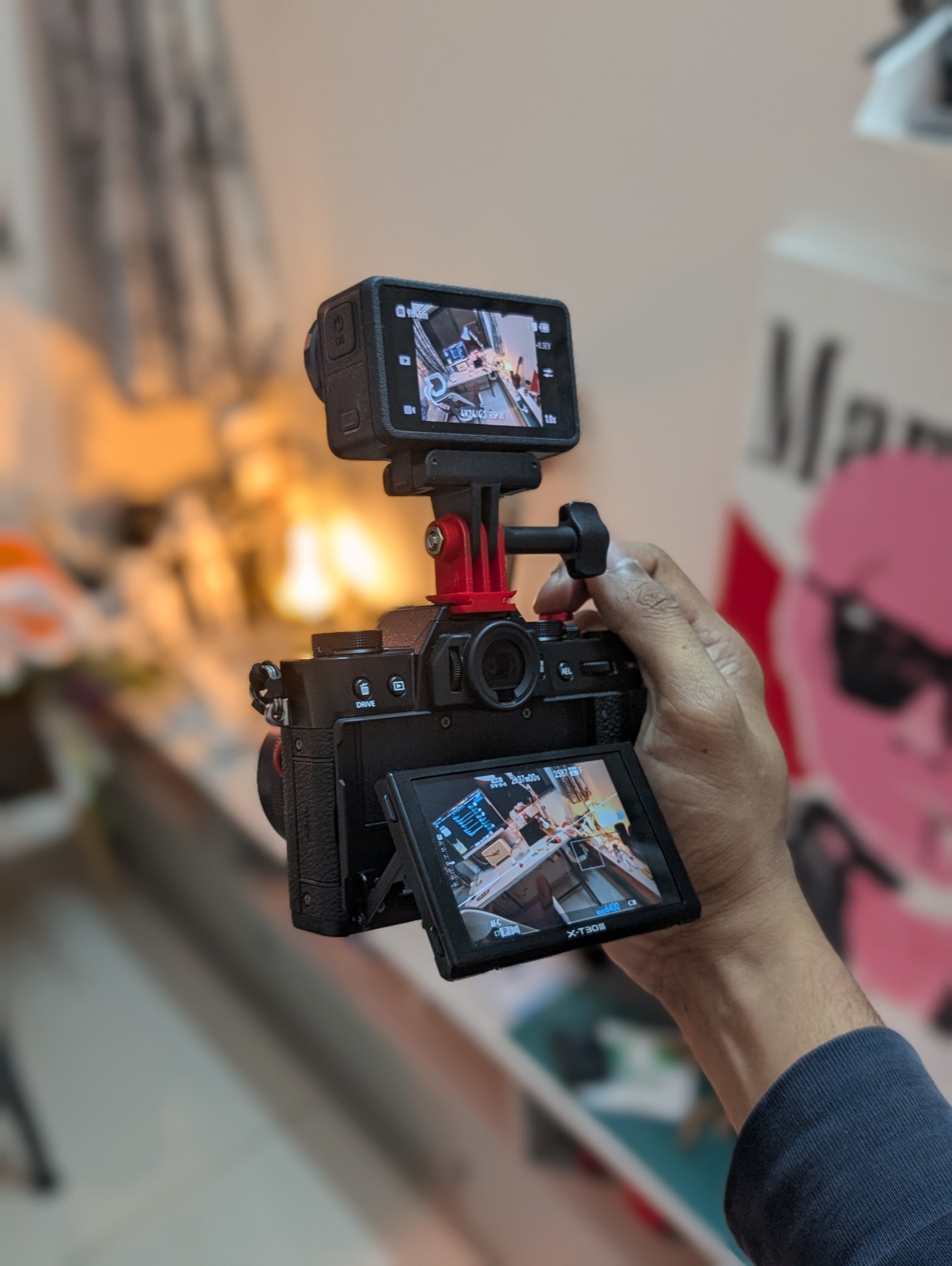 The finished rig held up mid-configuration: Fujifilm X-T30 III with a DJI Action 5 Pro on top via a 3D-printed hotshoe mount, both screens live