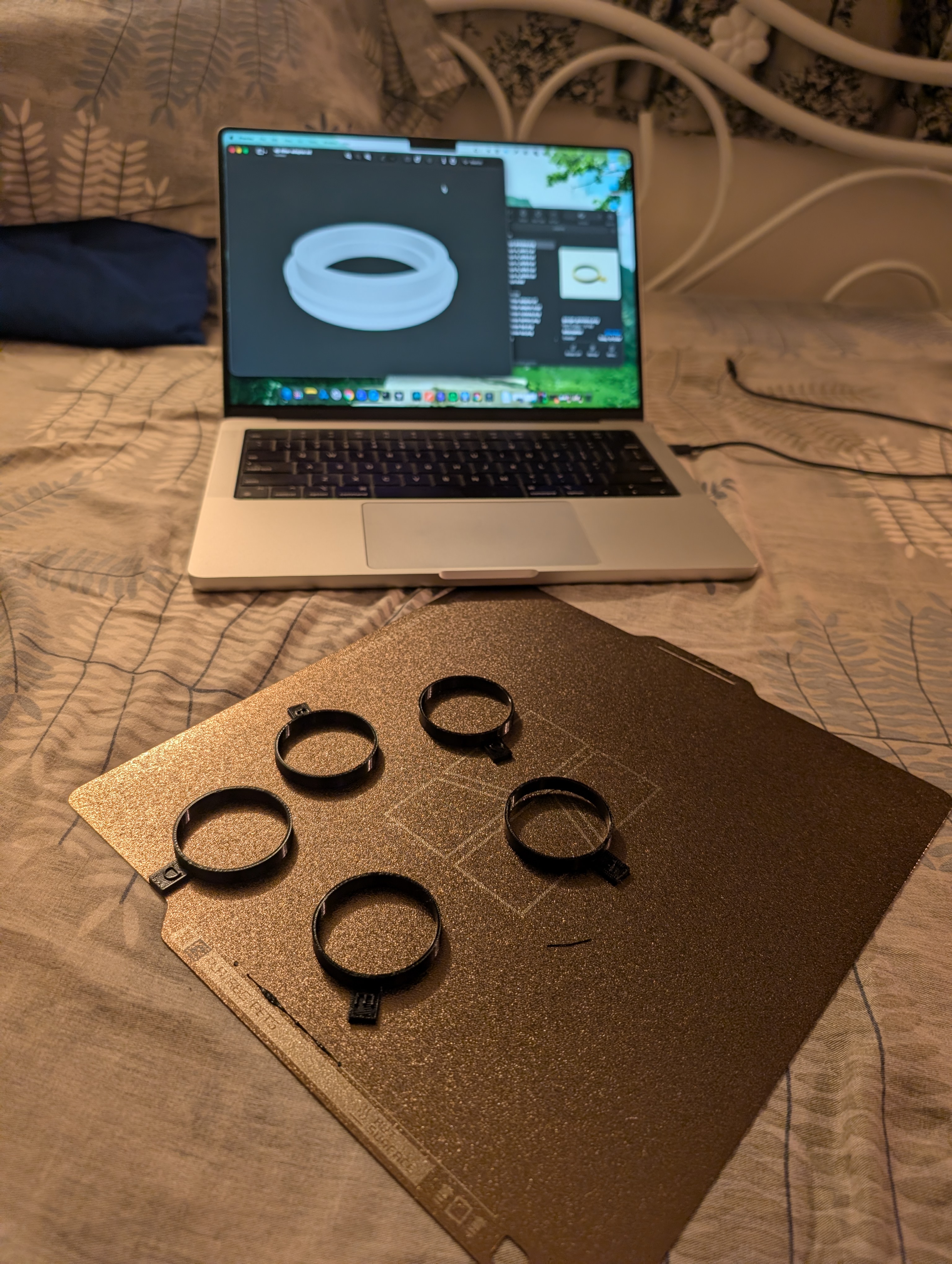Five printed fit-test rings on the build plate, with the CAD model on the laptop.